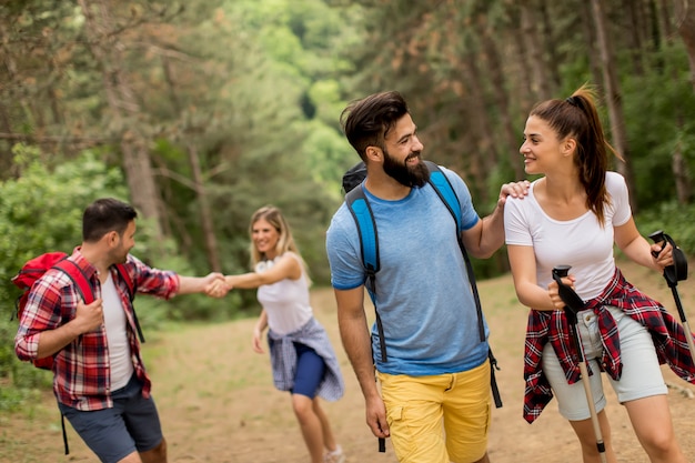 Giovane gruppo felice che fa un&#39;escursione insieme attraverso la foresta