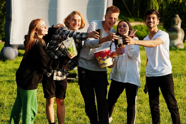 Giovane gruppo multietnico di persone che guardano film al poof nel cinema all'aperto.