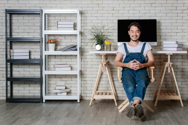 Giovane hipster barba uomo asiatico seduto con felice nel suo nuovo e moderno ufficio di avvio minimo, concetto per uomo d'affari felice all'inizio.