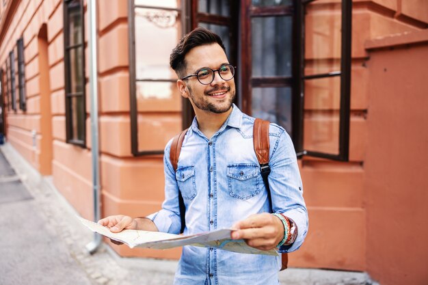 Giovane hipster carino in piedi in una città vecchia, tenendo la mappa e godersi la vista.