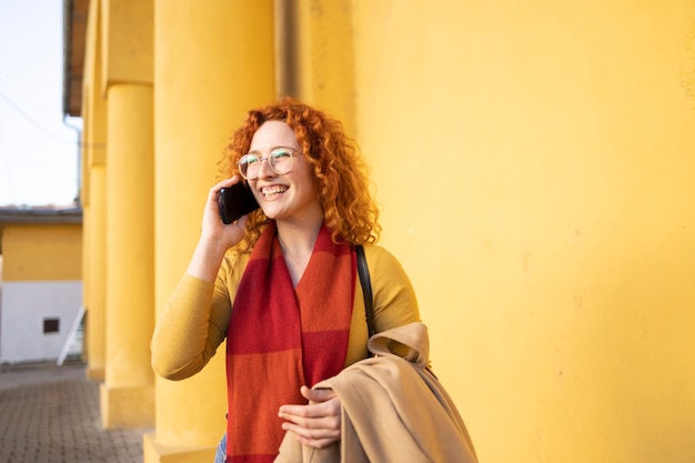 Giovane hipster femminile che parla con gli amici sul suo smartphone