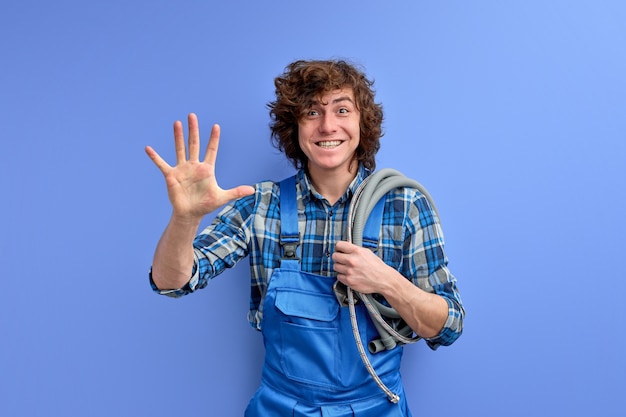 Giovane idraulico uomo che accoglie i clienti agitando la mano in telecamera isolate su blu di sfondo per studio.