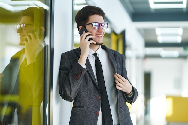 Giovane impiegato con gli occhiali utilizzando lo smartphone mobile L'uomo d'affari tiene il telefono in mano