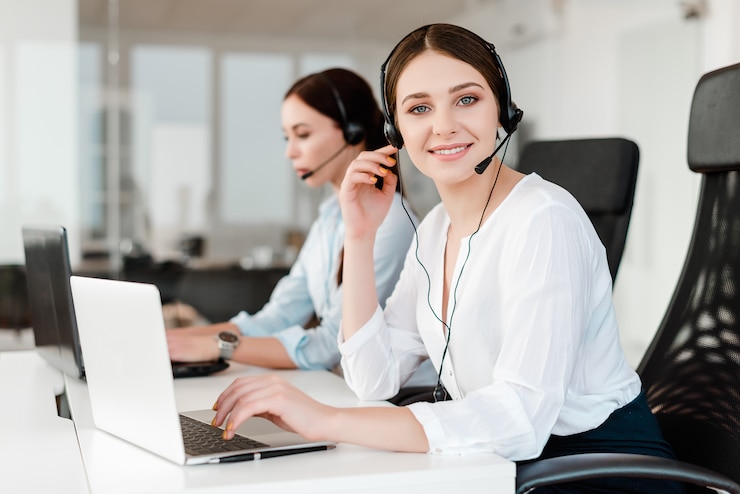 Giovane impiegato di concetto sorridente con una cuffia avricolare che risponde in un call center