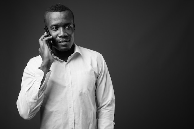 giovane imprenditore africano che indossa la camicia contro il muro grigio. bianco e nero
