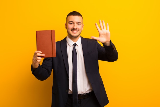 Giovane imprenditore bello su sfondo piatto con un libro di diario