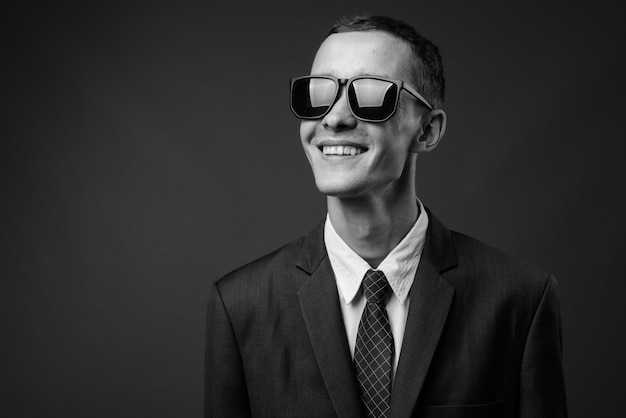 giovane imprenditore che indossa tuta contro il muro grigio in bianco e nero