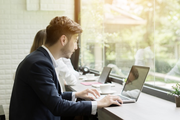 Giovane imprenditore che lavora al computer portatile in ufficio. Concetto di lavoro persone.