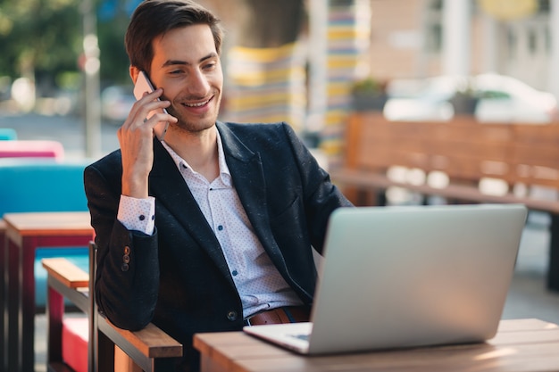 Giovane imprenditore che lavora su laptop e telefono