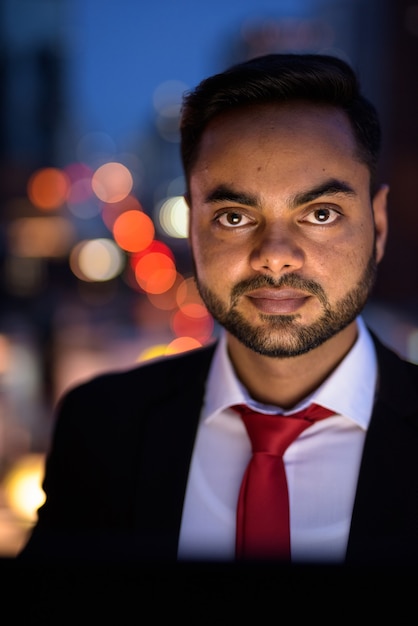 Giovane imprenditore indiano barbuto contro la vista della città di notte