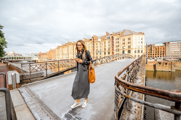 Giovane imprenditrice alla moda che cammina sul ponte nel famoso quartiere degli affari della città di Amburgo, Germania