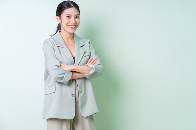 Giovane imprenditrice asiatica che indossa un abito verde su sfondo verde