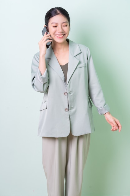 Giovane imprenditrice asiatica che tiene smartphone su sfondo verde