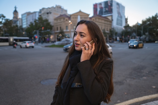 Giovane imprenditrice che cammina per la piazza e parla al telefono