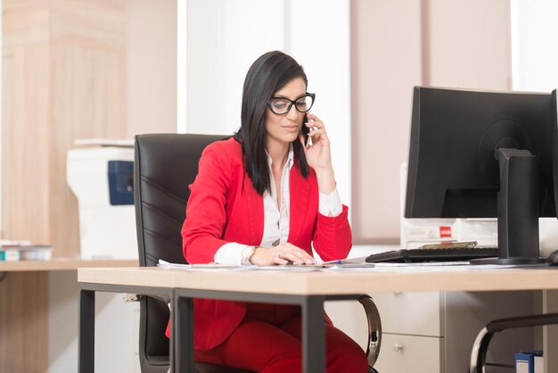 Giovane imprenditrice che lavora al suo computer mentre parla al telefono