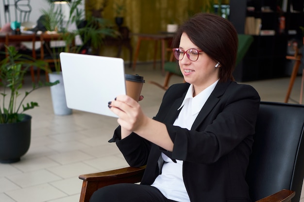 Giovane imprenditrice con videochiamata con tablet durante la pausa caffè