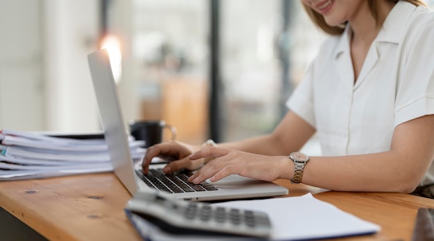 Giovane imprenditrice di successo seduta alla sua scrivania a lavorare sul computer portatile