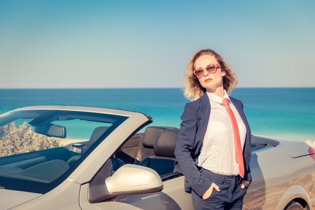 Giovane imprenditrice di successo sulla spiaggia Donna in piedi vicino all'auto d'epoca cabriolet