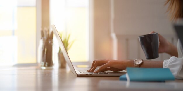 giovane imprenditrice lavorando con un computer portatile e bevendo una tazza di caffè