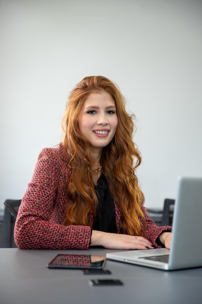 giovane imprenditrice rossa seduta davanti al computer guardando la fotocamera
