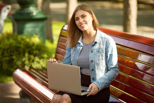 Giovane imprenditrice seduto nel parco e lavorando con il computer portatile