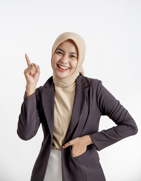 Giovane imprenditrice sorridente che indica lo spazio della copia, una mano in abiti tasca concetto di lavoro ufficio isolato sfondo bianco