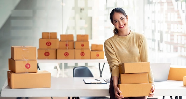 Giovane imprenditrice sorridente di successo con la sua piccola impresa Tenendo la cassetta dei pacchi controllando e preparando la consegna al cliente