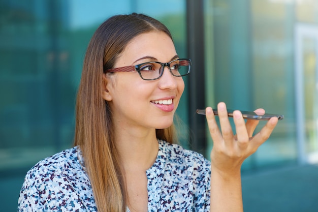 Giovane imprenditrice utilizzando il vivavoce del suo cellulare in strada