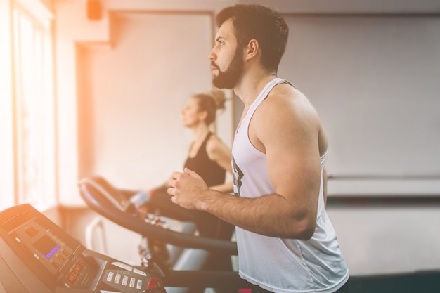 Giovane in abiti sportivi in esecuzione sul tapis roulant in palestra