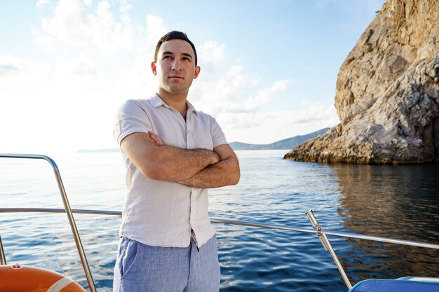 Giovane in camicia bianca in piedi sul naso yacht in mare