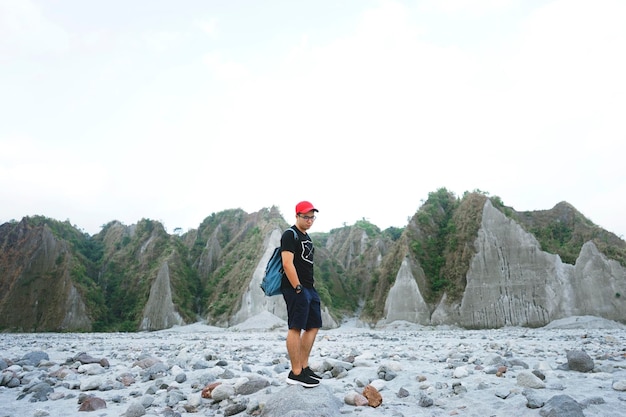 Giovane in piedi sulla spiaggia rocciosa