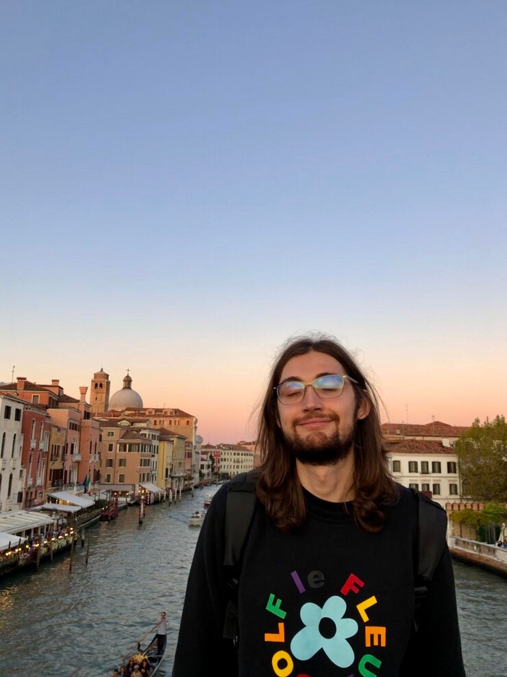 Foto giovane in piedi vicino al canale in città contro un cielo limpido