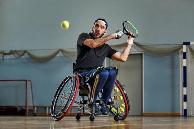 Giovane in sedia a rotelle che gioca a tennis sul campo Tennis sulla sedia a rotelle