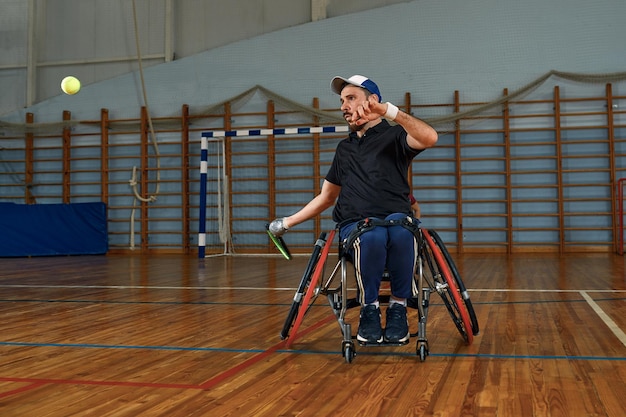 Giovane in sedia a rotelle che gioca a tennis sul campo