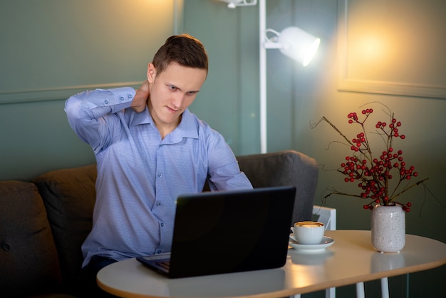 Giovane in un caffè che lavora su un computer portatile