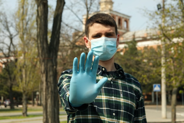 Giovane in una maschera protettiva e guanti nel parco