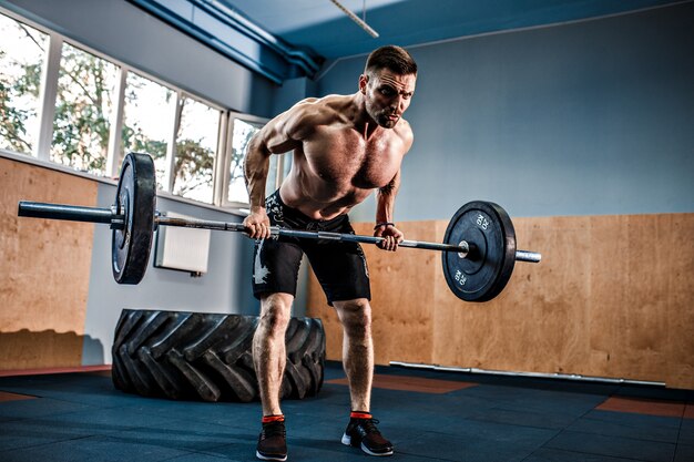 Giovane in una palestra di crossfit che alza un bilanciere.