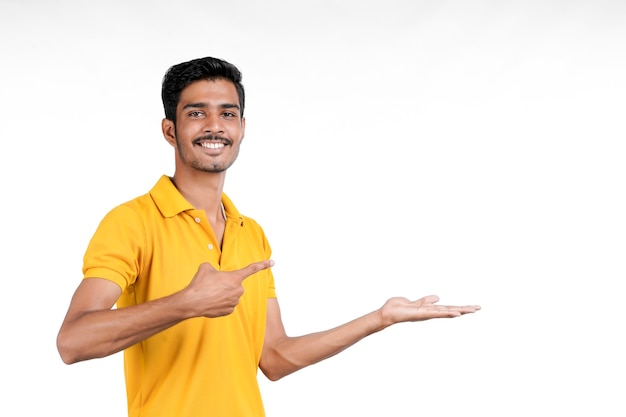 Giovane indiano che mostra l'espressione con la mano su sfondo bianco