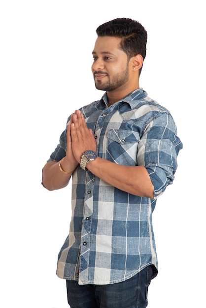 Giovane indiano con un'espressione di benvenuto o invitando o salutando Namaste su uno sfondo bianco