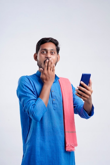Giovane indiano in abiti tradizionali e dando un'espressione scioccante dopo aver visto nel telefono cellulare