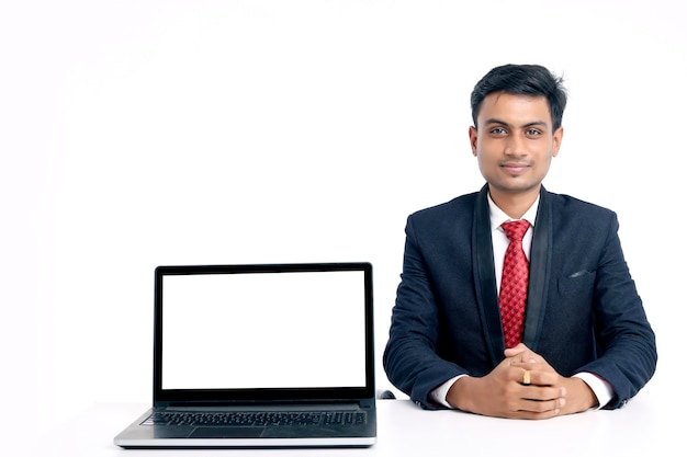 Giovane indiano in giacca e cravatta che lavora al computer portatile in ufficio