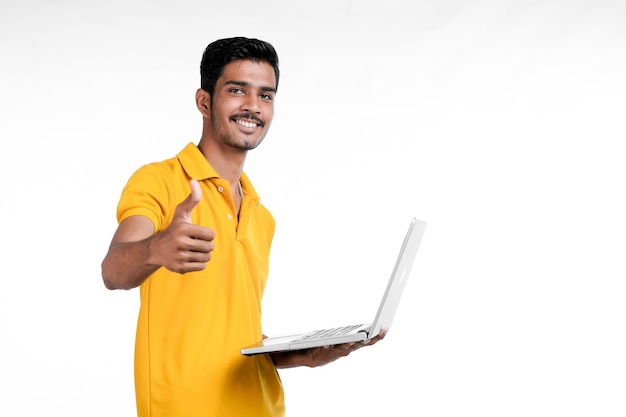 Giovane indiano utilizzando laptop su sfondo bianco.