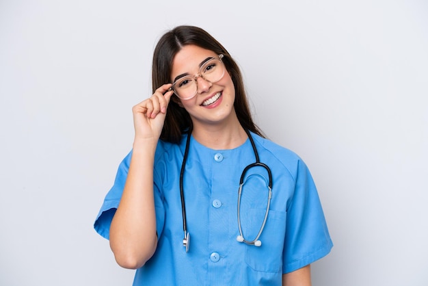 Giovane infermiera brasiliana donna isolata su sfondo bianco con gli occhiali e felice
