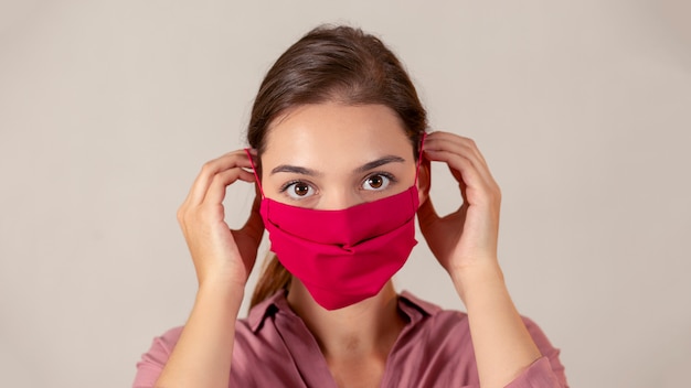 Giovane infermiera femminile che indossa una maschera medica in tessuto rosso durante la pandemia.