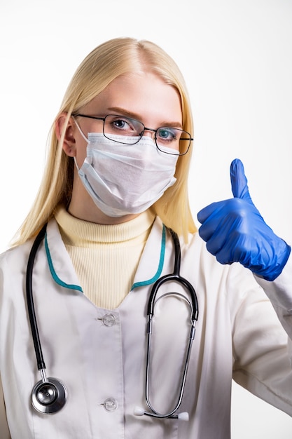 Giovane infermiera femminile in telecamera che indossa maschera chirurgica e scrub.