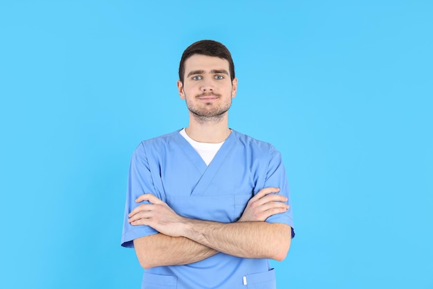 Giovane infermiera maschio attraente su sfondo blu