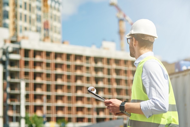 Giovane ingegnere civile che indossa il casco che ispeziona il concetto di ingegneria e architettura del cantiere