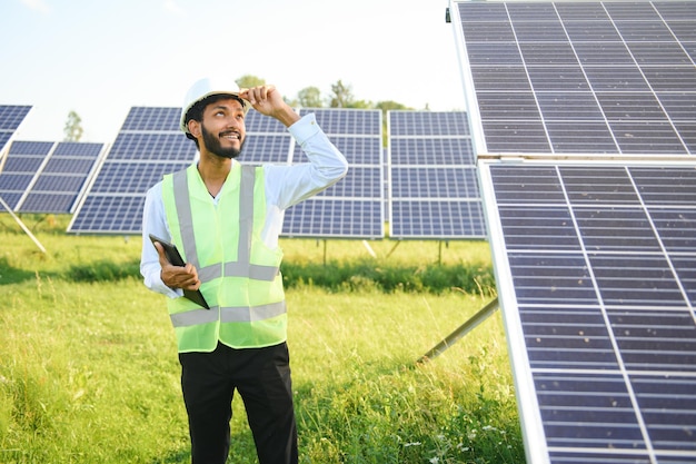 Giovane ingegnere con tablet in mano in piedi vicino a pannelli solari agricoltura terra agricola con sfondo blu limpido energia rinnovabile energia pulita