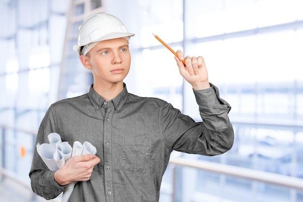 Giovane ingegnere maschio con il casco che tiene i progetti