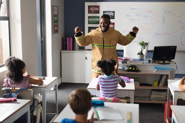 giovane insegnante afroamericano in uniforme di vigile del fuoco con studenti elementari multirazziali